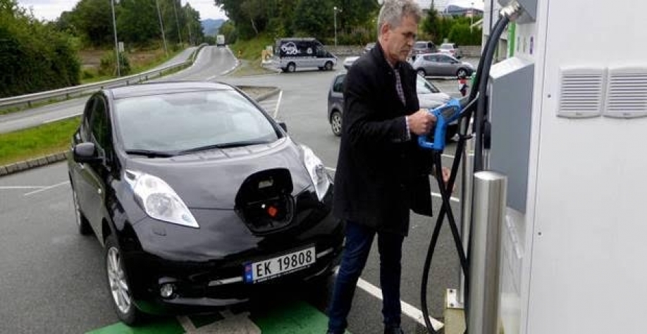 Homem carrega veículo elétrico em Finnoey, na Noruega