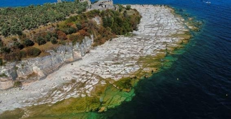 Legenda: Rochas subaquáticas emergem das águas do Lago de Garda depois que o norte da Itália passou pela pior seca em 70 anos em Sirmione, Itália. Foto Flavio Lo Scalzo/Reuters