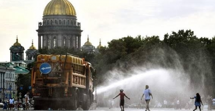 Legenda: Pedestres se refrescando através de serviço oferecido pela Prefeitura de São Petersburgo, na Rússia, durante onda de calor que atingiu a cidade em agosto deste ano. - (Olga Maltseva / AFP)